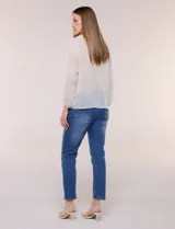 Blusa confeccionada en gasa semitransparente con sutil acabado plisado y estampado floral en tonos suaves. Presenta cuello solapa redondeado, escote en V y botonadura frontal. Mangas largas con puños elásticos y ruedo anudado en la parte inferior frontal.