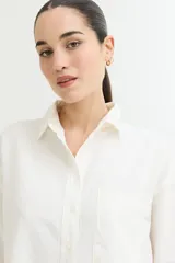 Camisa color beige de corte amplio, con cuello clásico, manga larga y bolsillo en el pecho.