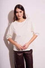 Remera de algodón color blanco roto, con escote redondo y mangas globo de tres cuartos con elástico en el puño.