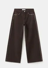 Jeans de corte recto y tiro medio color marrón, con detalles de tachas metálicas en las costuras laterales.