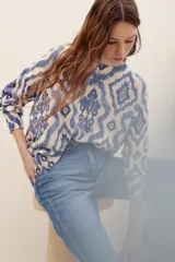 Sweater de punto color crudo con estampado geométrico en tonos azules, cuello redondo y mangas largas.