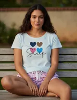 Pijama compuesto por una remera celeste de manga corta con estampado de corazones de colores y la palabra 'Sleep', y un short rosado con estampado de corazones y lazo ajustable en la cintura.