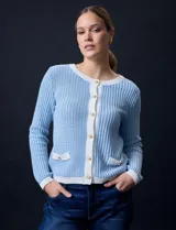 Cardigan de tejido tweed celeste y blanco, con escote redondo, cierre frontal con botones metálicos dorados y bolsillos simulados en el frente.