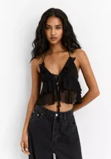 Top negro corto con breteles finos, escote en V con volados y detalle de lazo en el centro.