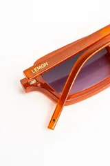 Lentes de sol con armazón rectangular de acetato color ocre translúcido y cristales degradados en tono violeta.