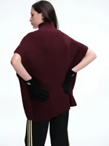 Chaleco tipo poncho de tejido de punto color tostado, con cuello polera y diseño holgado con laterales abiertos.