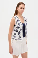 Chaleco sin mangas de algodón color blanco, con escote en V y bordados florales en azul marino.