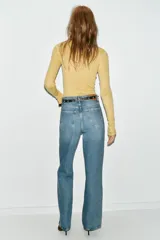 Jeans de tiro alto color azul claro, con cinco bolsillos y pernera recta que se estrecha hacia el tobillo. Incluye un cinturón negro con detalles metálicos. Cierre frontal con cremallera y botón.