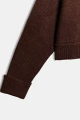 Jersey de punto color azul eléctrico con escote en pico, manga larga y detalle de costuras marcadas en los hombros. Presenta un corte ligeramente cropped con puños y ruedo acanalados.