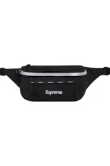 Riñonera Supreme color negro, con bolsillo frontal de malla, detalle reflectante en la parte superior y logo de la marca estampado en el frente.