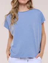Remera de silueta amplia y relajada confeccionada en algodón y poliéster, de color verde, con escote a la base y mangas cortas de hombro caído. Presenta dobladillo enrollado y ruedo curvo.