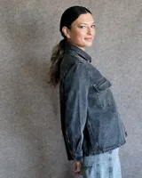 Sobrecamisa de denim azul con cuello camisero, cierre frontal con botones, mangas largas con puños abotonados y dos bolsillos con solapa en el pecho.