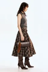 Chaleco de punto gris oscuro, sin mangas, con cuello camisero y tapeta de botones. Presenta un acabado de punto acanalado en las sisas y el bajo.