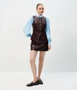 Camisa de crepé color blanco, con cuello inglés, manga larga abullonada con puños abotonados y cierre frontal oculto con botón diferenciado en el cuello.
