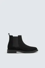 Bota estilo Chelsea de hombre, confeccionada en piel con acabado de serraje. Presenta elásticos laterales, horma redonda y suela a tono con ligero tacón.