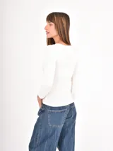 Remera de manga larga con diseño de rayas horizontales finas en blanco y negro, cuello redondo y corte ajustado.