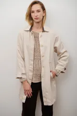 Spolverino largo de jean color azul, con cuello camisero, botones frontales y costuras decorativas en blanco.