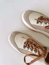 Championes de cuero color visón con cordones marrones, suela blanca y base color caramelo.