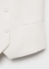 Chaleco blanco con cuello escotado, cierre de doble botonadura, dos bolsillos delanteros de ribete y tirantes anchos. Diseño recto con forro interior.