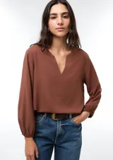 Blusa de viscosa color marrón con escote en V, mangas tres cuartos con puños elásticos y corte holgado.