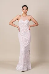 Vestido largo de tul color nude, con bordados blancos de diseño floral. Presenta escote redondo, corte ajustado y falda con vuelo.