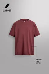 Camiseta de entrenamiento de ajuste relajado, color vino tinto, confeccionada en tejido de peso medio con mezcla de algodón. Presenta cuello redondo con acabado en vivo doble y manga corta.