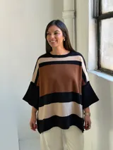 Poncho de tejido de punto con diseño de rayas horizontales anchas en tonos negro, marrón y beige, con cuello redondo y mangas amplias.