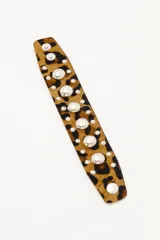Pulsera de cuero vacuno con estampado animal print tipo leopardo, decorada con tachas metálicas plateadas de diferentes tamaños y cierre con broches a presión.