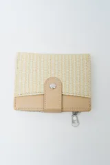 Billetera plegable color beige y crudo, con textura tejida en la parte superior y detalles en cuero liso beige en la solapa de cierre a presión y el borde inferior. Posee un bolsillo exterior con cierre metálico.
