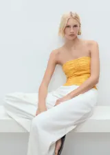 Top bandeau amarillo con diseño fruncido en el cuerpo, sin mangas y cierre de cremallera en la espalda.