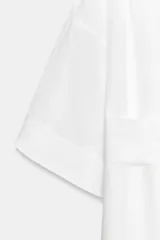 Vestido tipo túnica de corte evasé, color blanco, con escote en pico, mangas por debajo del codo y cinturón ajustable del mismo tejido.