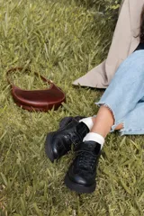 Zapato Oxford negro de cuero con cordones, suela track y detalle de aplique con logo en la lengüeta.