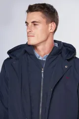 Campera de abrigo azul marino resistente al agua con capucha desmontable, cierre metálico y botones a presión personalizados. Tiene bolsillos en el frente y dos bolsillos internos.