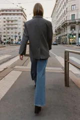 Blazer de corte oversize en color gris jaspeado, con cuello solapa, hombreras y cierre frontal cruzado con botones. Cuenta con bolsillos delanteros con solapa.