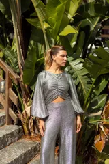 Pantalón de tiro alto confeccionado en tejido de lamé dorado con acabado brillante y corte ligeramente evasé.