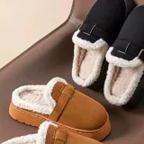Pantuflas de gamuza color marrón tostado, sin talón, con plataforma baja, forro interno de corderito sintético y tira con hebilla decorativa en el empeine.