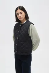 Chaleco acolchado de color negro con diseño de rombos, cierre frontal con botones metálicos a presión y dos bolsillos delanteros aplicados.