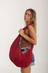 Cartera hobo grande de cuero descarne color marrón, con correa de hombro ajustable y cierre superior con cremallera.