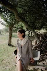 Tapado de corte recto y largo midi, confeccionado en tejido con textura de espiga en tonos grises. Presenta solapas clásicas, cierre frontal con botones y bolsillos laterales amplios con solapa.