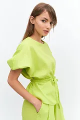 Blusa color verde lima, de manga tres cuartos con leve volumen y largo hasta la cadera. Incluye cinto extraíble en espalda que permite anudar para modificar la silueta.