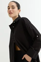 Camisa color crudo, de corte clásico, con cuello camisero, cierre frontal con botones y mangas 3/4 con trabillas.