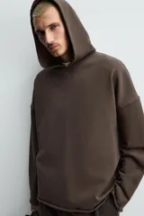 Sudadera tipo hoodie de corte relajado, confeccionada en tejido de algodón con interior de rizo. Presenta cuello con capucha, manga larga y acabados con bordes enrollados.