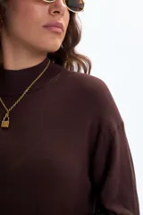 Vestido largo de tejido de punto color marrón oscuro, de manga larga y cuello alto.