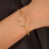 Pulsera de malla metálica con dije central en forma de corazón, ambos en acabado dorado.