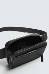 Riñonera negra con textura grabada, compartimento principal con cierre de cremallera y bolsillo frontal plano. Incluye asa ajustable con hebilla metálica de liberación rápida.