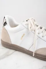 Zapatillas deportivas de cuero blanco con puntera y talón en gamuza color beige. Detalle de pelo animal print en el talón y suela de goma color caramelo.