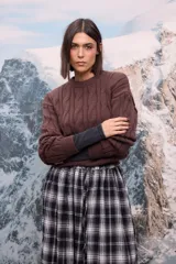 Buzo de punto grueso en color beige, con diseño de trenzas verticales y cuello redondo.