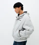Campera bomber de poliamida en color gris claro, con capucha, cierre frontal con botones a presión y lettering bordado en el pecho. Presenta un diseño funcional con detalles utilitarios.
