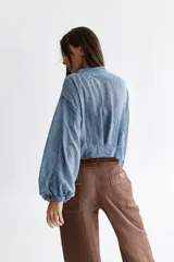 Camisa celeste de voile de algodón con cuello a la base y mangas balloon. Cierre frontal con lazos en la misma tela.