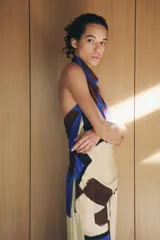 Top de cuello halter con hombros descubiertos, espalda descubierta, detalle de drapeado lateral y bajo asimétrico.